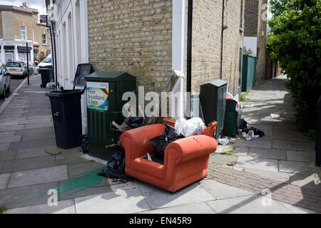 Dumped armchair and other domestic rubbish, fly-tipped on a street corner in south London. Stock Photo