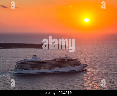 Cruise ship departing Santorini by the evening sunset headed for a new destination, Thera, Greece. Stock Photo