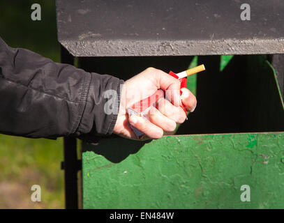 man's hand breaks a pack of cigarettes about a waste bin closeup outside Stock Photo