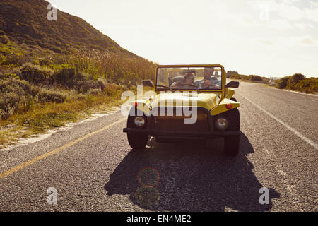 Young couple driving in a car on a open road. Young couple on road trip on summer day. Stock Photo