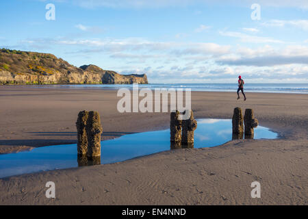 Man running on beach just after sunrise at Sandsend, North Yorkshire, UK. Stock Photo