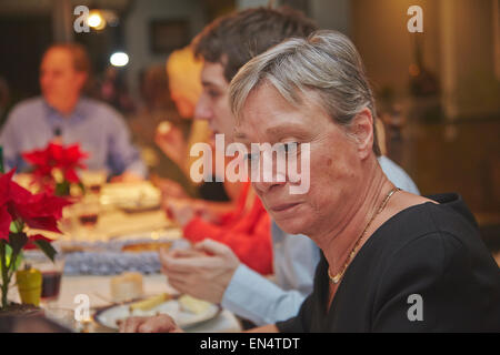A mature woman at a New Year's Eve family dinner party, with a mixed age range; in Brussels, Belgium. Stock Photo
