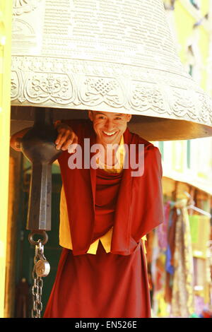 smiling happy monk under ceremonial bell. Kathmandu, Nepal.boudhanath temple Stock Photo