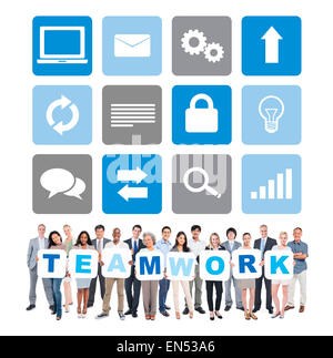 Group of Multi-Ethnic Business People Holding Letters that forms "TEAMWORK" with Computer Icons Above Them Stock Photo
