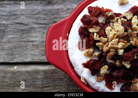 Brie Cranberry and walnuts in a pot ready for the oven on old wooden planks Stock Photo