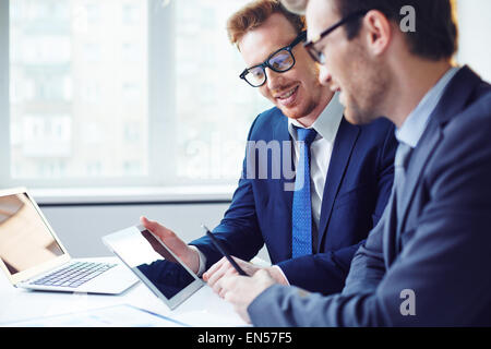 Two young co-workers using modern gadgets at meeting Stock Photo
