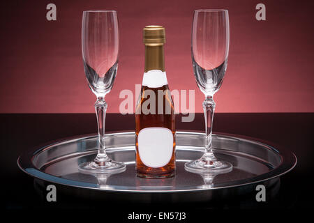 Two champagne glasses and a bottle of sparkling wine on a silver tray Stock Photo