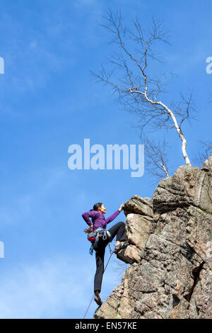 Female happy rock climber on a steep cliff. Stock Photo