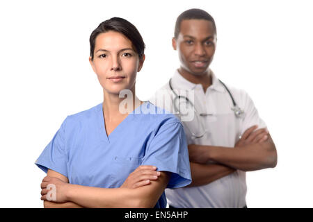 Successful attractive female doctor or surgeon in scrubs standing with folded arms in front of an African male doctor or consult Stock Photo