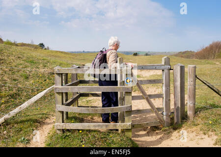 Senior walker walking in kissing gate on Wales Coast Path in Oxwich National Nature Reserve on Gower Peninsula Swansea Wales UK Stock Photo
