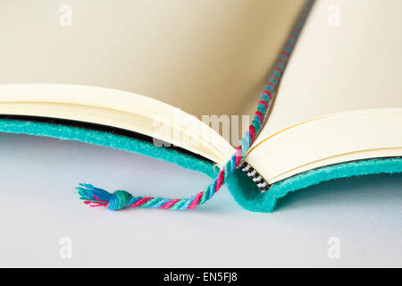 Open blank notebook note book with a bookmark marking the page on a plain surface with copy space on white background. Stock Photo