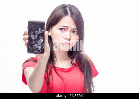 Frowning Chinese woman holding cell phone with cracked screen Stock Photo