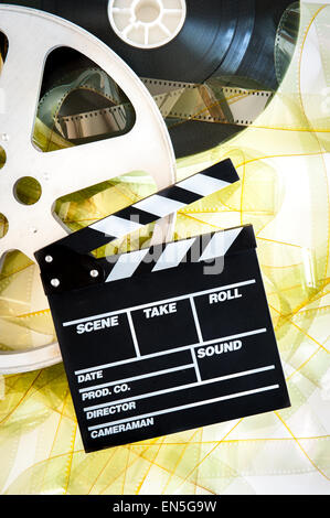 Movie clapper on 35mm yellow unrolled film and cinema reels on neutral background vertical frame Stock Photo