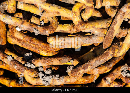 A pile of rusty obsolete chains contaminated with cement. Bright brown color. Industrial waste. Stock Photo