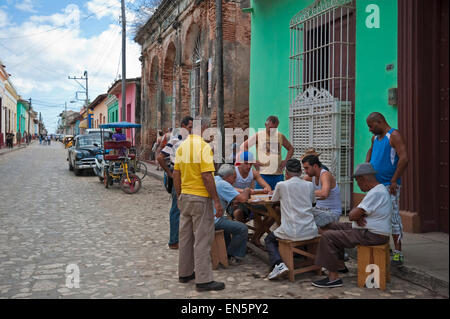 Horizontal view of a group of Cubans playing dominoes on the side of the road in Trinidad, Cuba. Stock Photo