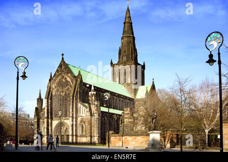 Tourists in Cathedral Square in front of the main entrance of St Mungo's Cathedral, Glasgow. Lamp-posts holding Glasgow coat of Stock Photo