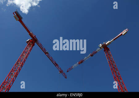red cranes against a blue sky on a construction site Stock Photo