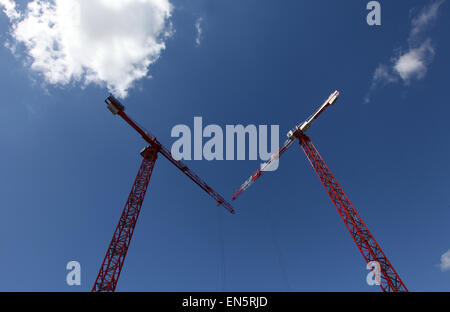 red cranes against a blue sky on a construction site Stock Photo