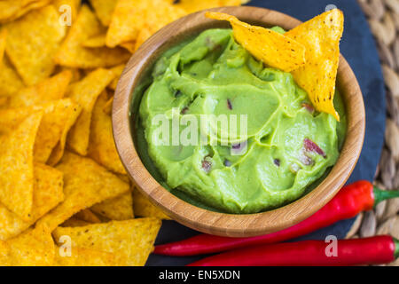 Guacamole in Wooden Bowl with Tortilla Chips and Chilli Stock Photo