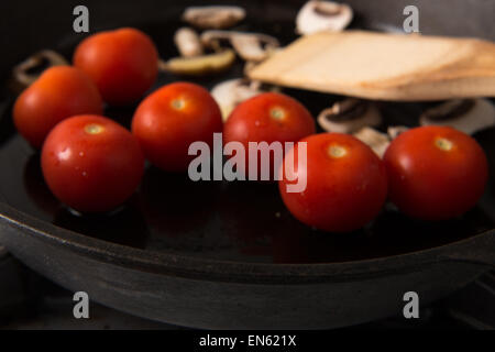 Series: Grilling Strip Loin Steak in Cast Iron Frying Pan: Ingredients sliced mushrooms and tomatoes prepared first - selective Stock Photo