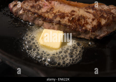 Series: Grilling Strip Loin Steak in Cast Iron Frying Pan: Steak in the frying pan with butter Stock Photo