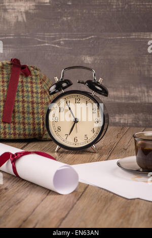 Old clock, hat coffee and paper sheets on old Wooden table. Stock Photo