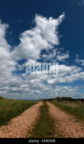 A gravel path leading into the distance with clouds against a blue sky Stock Photo