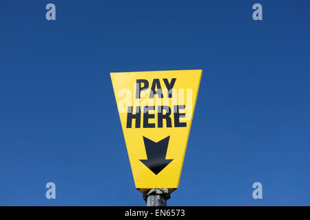 Yellow pay here sign against a blue sky background with copy space Stock Photo