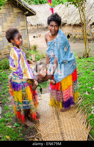 South Pacific Islander women demonstrating with a child a traditional stretcher made from leaves. Tanna, Vanuatu. Pacific islanders, cultural Stock Photo