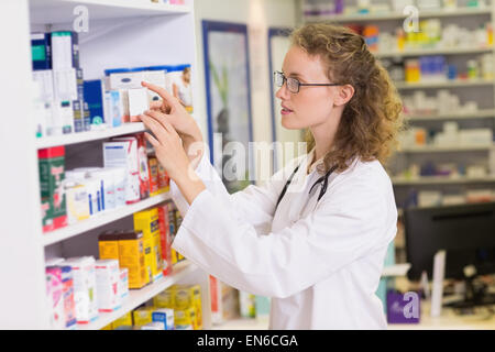 Smiling pharmacist taking jar from shelf Stock Photo - Alamy