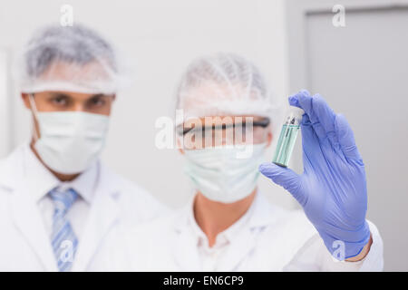 Scientists examining green precipitate in tube Stock Photo