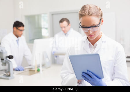Scientist using tablet while colleagues working behind Stock Photo