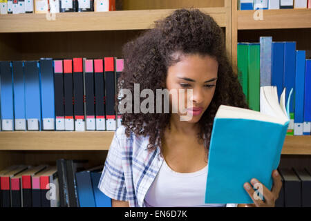 Pretty student sitting on floor in library Stock Photo