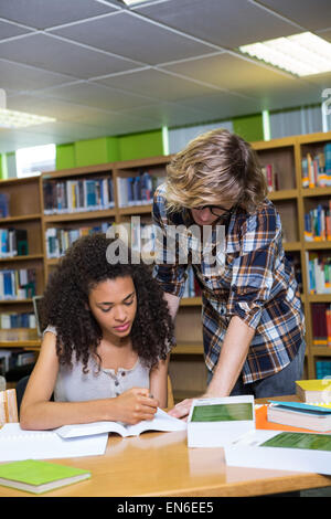 Student getting help from classmate in library Stock Photo