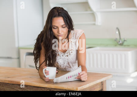 Pretty brunette reading newspaper with a mug Stock Photo