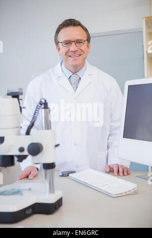 Happy scientist looking at camera with hands on table Stock Photo