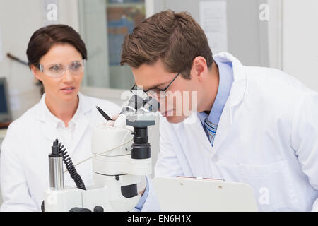 Scientists looking attentively in microscope Stock Photo