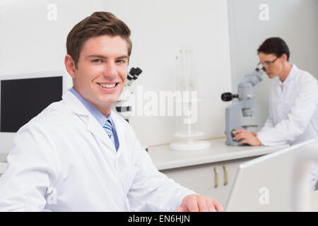Scientist working with laptop and another with microscope Stock Photo