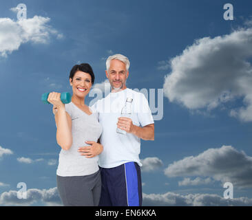 Composite image of happy fit couple with dumbbell and water bottle Stock Photo