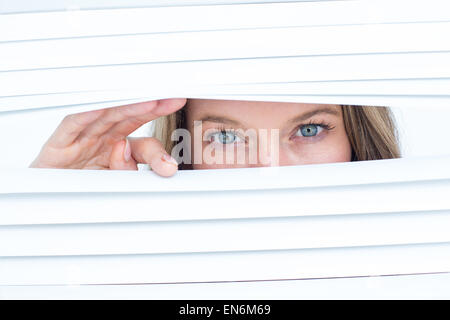 Woman peering through roller blind Stock Photo