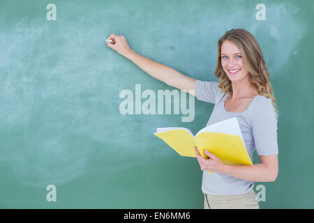 Smiling teacher writing on blackboard Stock Photo