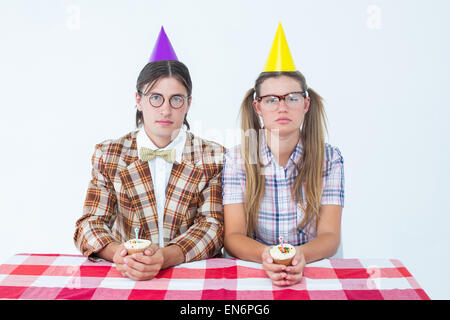Unsmiling geeky hipsters celebrating birthday Stock Photo