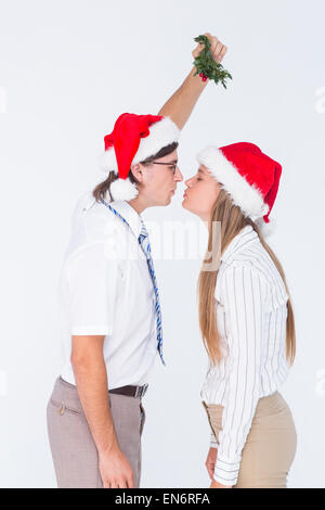 Geeky hipster kissing under mistletoe Stock Photo