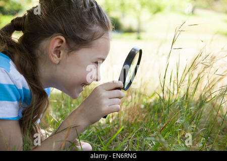 Cute little girl looking through magnifying glass Stock Photo