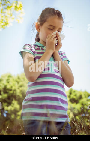 Cute little girl blowing her nose in park Stock Photo