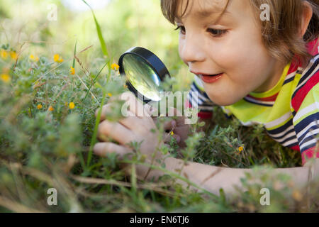 Happy little boy looking through magnifying glass Stock Photo