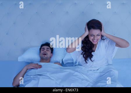 Woman covering ears while man snores Stock Photo