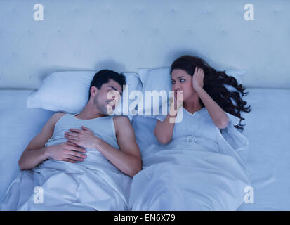 Woman covering her ears while man snores Stock Photo