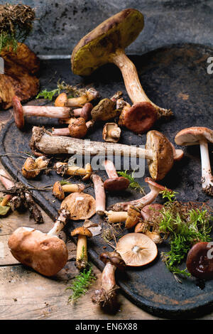 Mix of forest mushrooms on black cutting board over old wooden table. See series Stock Photo