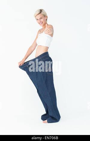Blonde wearing too large pants with the thumb up Stock Photo